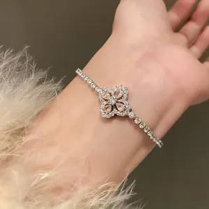 Close-up detail view of a dainty silver bracelet with a champagne zircon flower charm.