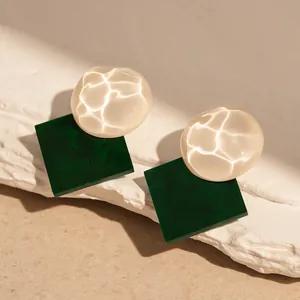 Close-up of green square resin earrings with white shimmering water ripple texture detail
