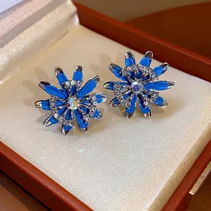 Elegant flower stud earrings with blue enamel petals and sparkling crystals in a gift box.