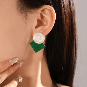 Close-up of vintage resin earrings with green square and rippled white round studs.