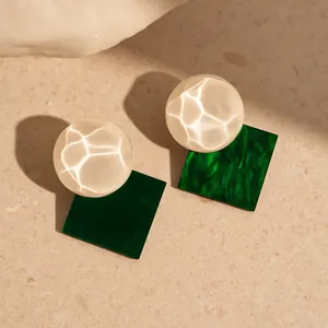 Detailed close-up of retro shimmering resin stud earrings with a green square base design