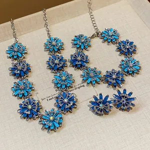Detail view of a vintage-style blue flower jewelry set with necklace, bracelet, and earrings.