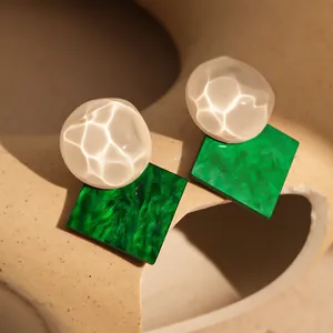 Macro detail of vintage resin stud earrings featuring shimmering white and green elements