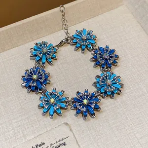 Detailed view of a vintage-style bracelet with blue enamel flowers and sparkling rhinestones.