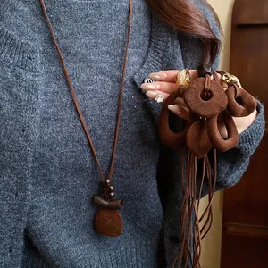 Detailed view of vintage brown flocked pendant necklace styled on grey cardigan