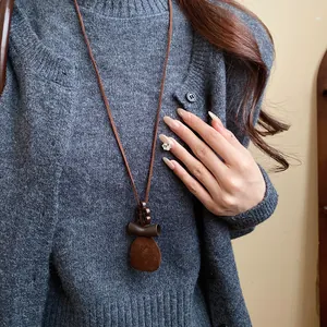 Close-up of retro brown flocked pendant necklace worn over a grey knit cardigan