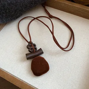 Detailed view of a vintage flocked flower pendant necklace with brown velvet cord