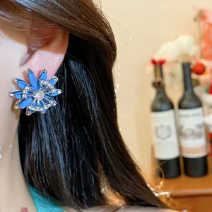 Detailed close-up of a blue flower earring with crystal and interlocking logo decoration