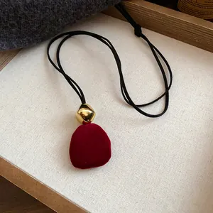 Detailed view of a vintage red flocked flower pendant necklace with gold accent bead
