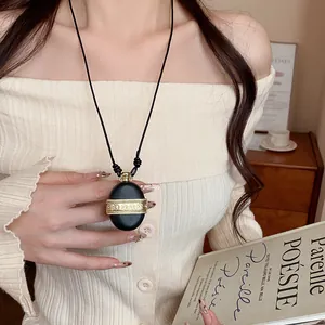 Vue détaillée d'un collier pendentif bouteille d'eau en cuir avec bande dorée zircon