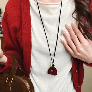 Close-up detail of a vintage red flocked flower pendant necklace with black cord