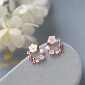 Vista macro dettagliata di eleganti orecchini a ghirlanda con perle bianche e cristalli rosa.