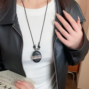 Vue détaillée d'un collier pendentif en pierre vintage avec bandes de zircon sur veste.