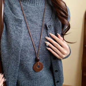 Detail of vintage brown flocked pendant necklace worn with gray knitted cardigan