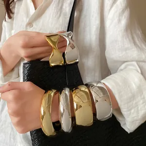 Close-up of glossy twisted and wide metallic bangles in gold and silver finishes