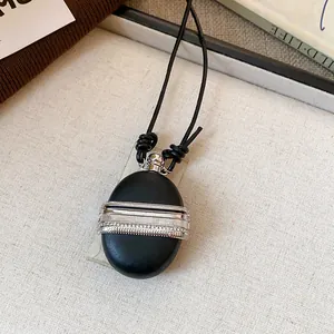 Gros plan d'un collier pendentif fiole en cuir noir rétro avec bande en argent zircon.