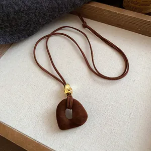 Close-up of vintage brown flocked pendant necklace with golden bead detail