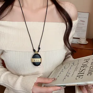 Détail du collier avec pendentif galet vintage et bande de zircon doré sur cordon cuir
