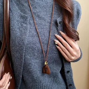 Detailed view of a vintage flocked flower pendant necklace on a brown suede cord