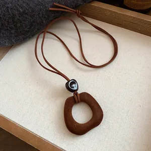 Detailed shot of a vintage brown flocked pendant necklace with a soft suede cord