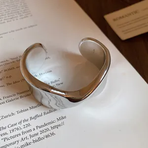 Close-up of a high-gloss silver twisted open cuff bracelet on a vintage page.