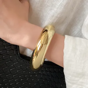 Close-up of a high-polish gold chunky bracelet worn on a wrist