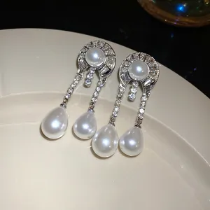 Primo piano di orecchini pendenti vintage eleganti con diamanti e perle a goccia.
