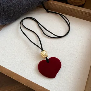 Close-up of retro red flocked heart pendant necklace with gold metallic bead detail.