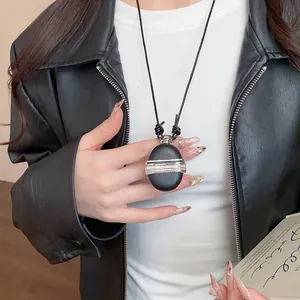 Détail d'un collier pendentif rétro en cuir et zircon sur une veste en cuir noir.