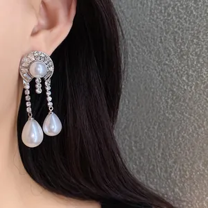 Primo piano di eleganti orecchini a goccia con perle vintage e strass su ago argento.