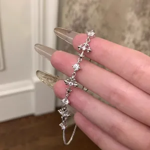 Detailed view of vintage silver zircon fleur-de-lis cross bracelet on hand