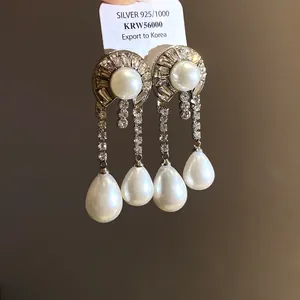 Primo piano di orecchini vintage in argento con perle, strass e etichetta chiara