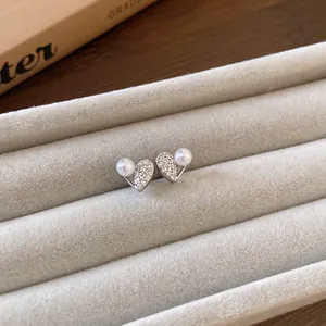 Primo piano di orecchini a cuore in argento con brillanti pavé di zirconi e piccole perle