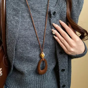 Detailed view of a vintage brown flocked oval pendant on a long faux suede cord necklace