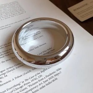 Macro view of a minimalist chunky silver twisted bangle resting on a vintage book
