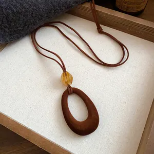 Detailed view of retro necklace with dark brown flocked oval pendant and amber resin bead