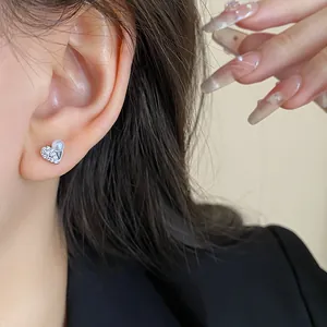 Dettaglio ravvicinato di un orecchino a forma di cuore con zirconi e perle bianche