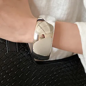 Close-up shot of a minimalist wide silver open cuff bracelet worn on a woman's wrist