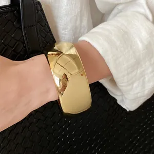 Detailed close-up of a minimalist gold polished twisted open cuff bracelet worn on wrist