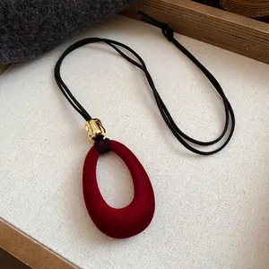 Detailed view of a vintage burgundy velvet oval pendant necklace with a gold-textured bead.
