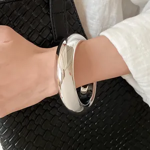 Close-up view of a minimalist silver twisted open cuff bracelet styled on the wrist
