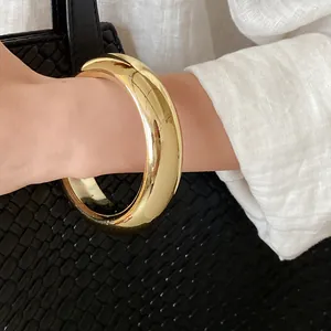 Elegant chunky gold-plated bangle bracelet with high-polish finish worn on wrist