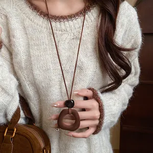 Detailed close-up of a vintage brown flocked geometric pendant necklace on a cream sweater