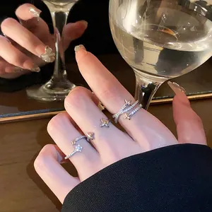 Detailed macro view of sparkling zircon star open rings worn on hand with wine glass