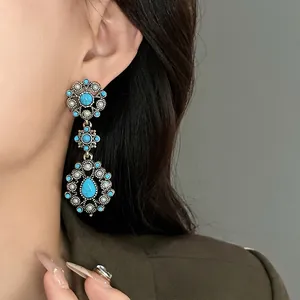 Elegant vintage flower drop earrings with blue turquoise and pearls worn by a model