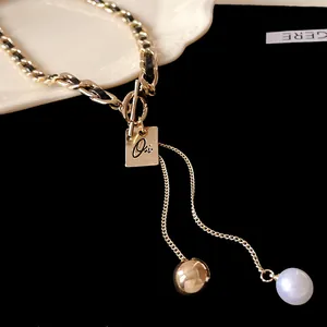 Gros plan d'un collier chaîne dorée avec tressage en cuir et pendentif Oui.