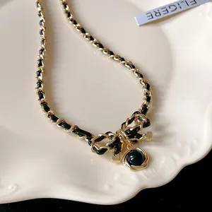 Détail macro d'un collier à nœud vintage avec chaîne en cuir et perle noire.