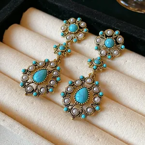 Close-up detail of vintage floral teardrop earrings with turquoise stones and pearls.