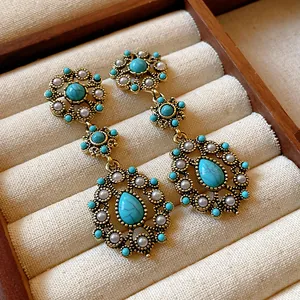 Detailed view of vintage gold-tone dangle earrings with turquoise stones and delicate pearls