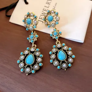 Detailed view of vintage turquoise flower and waterdrop dangle earrings in gold metal